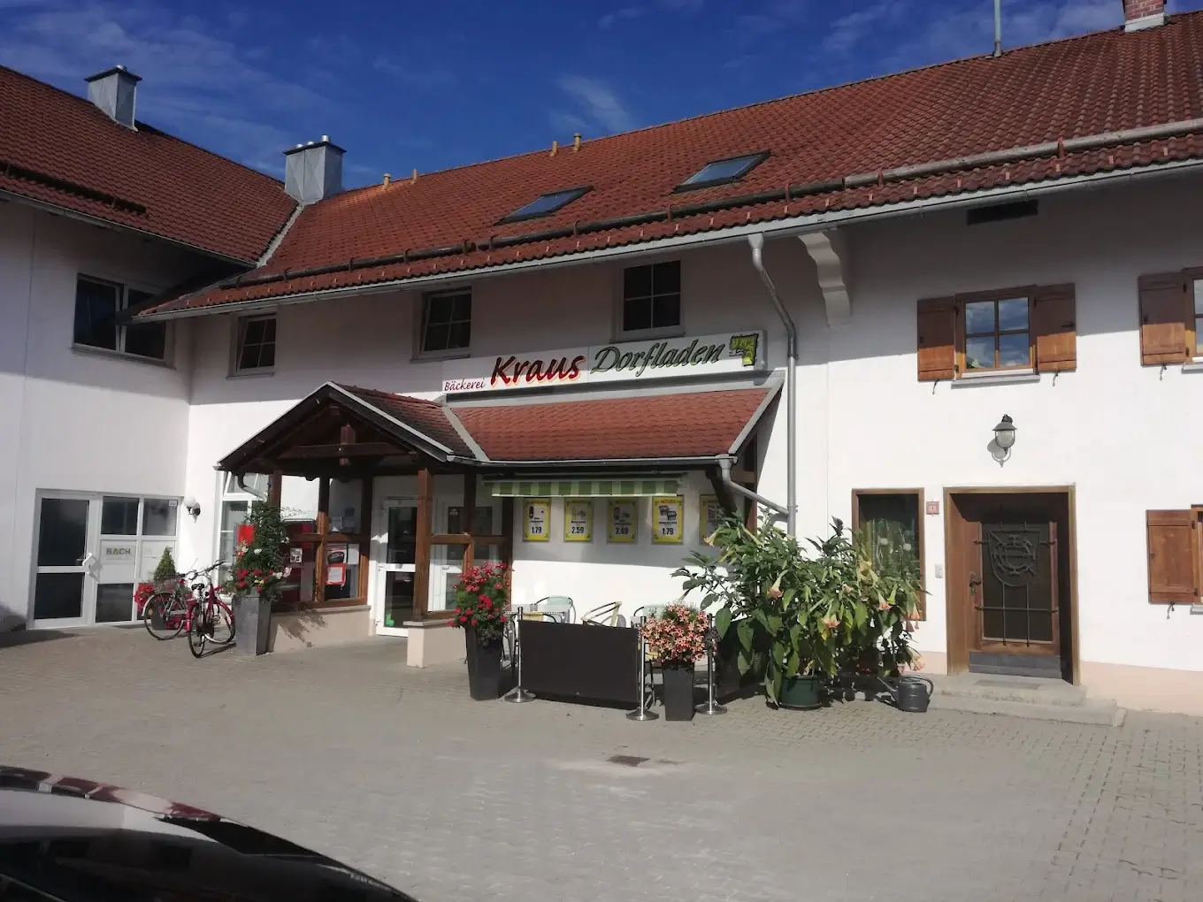 Eingang der Bäckerei Kraus mit Dorfladen in Leuterschach, davor Blumen und ein abgestelltes Fahrrad