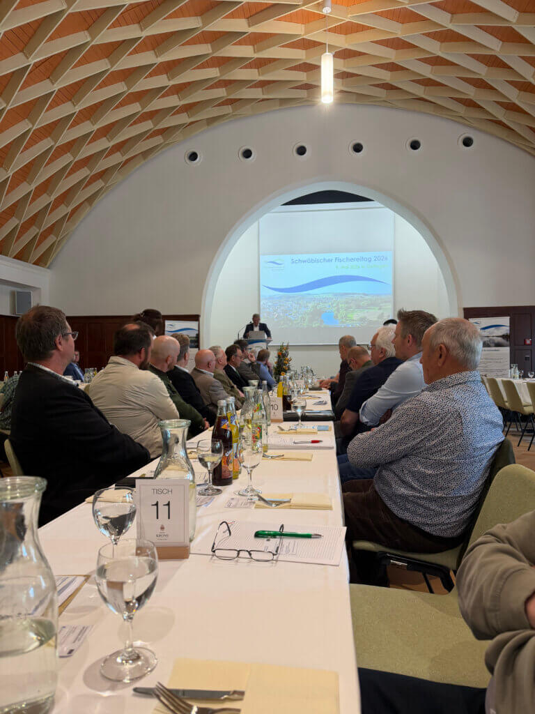 Delegierte des Schwäbischen Fischereitags 2026 im Festsaal in Oettingen, im Hintergrund Rednerpult und Leinwand mit dem Verbandslogo