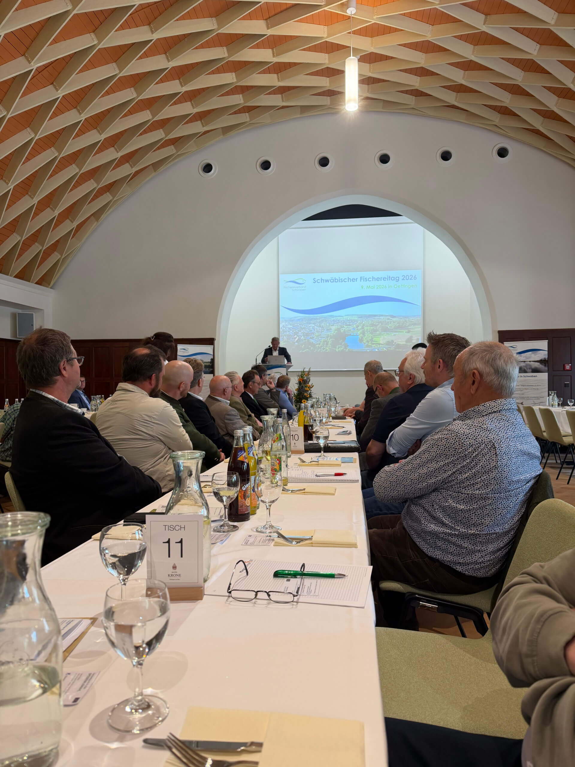 Delegierte des Schwäbischen Fischereitags 2026 im Festsaal in Oettingen, im Hintergrund Rednerpult und Leinwand mit dem Verbandslogo